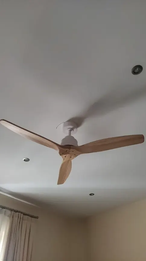 Ventilador de techo con aspas de madera instalado en un salón